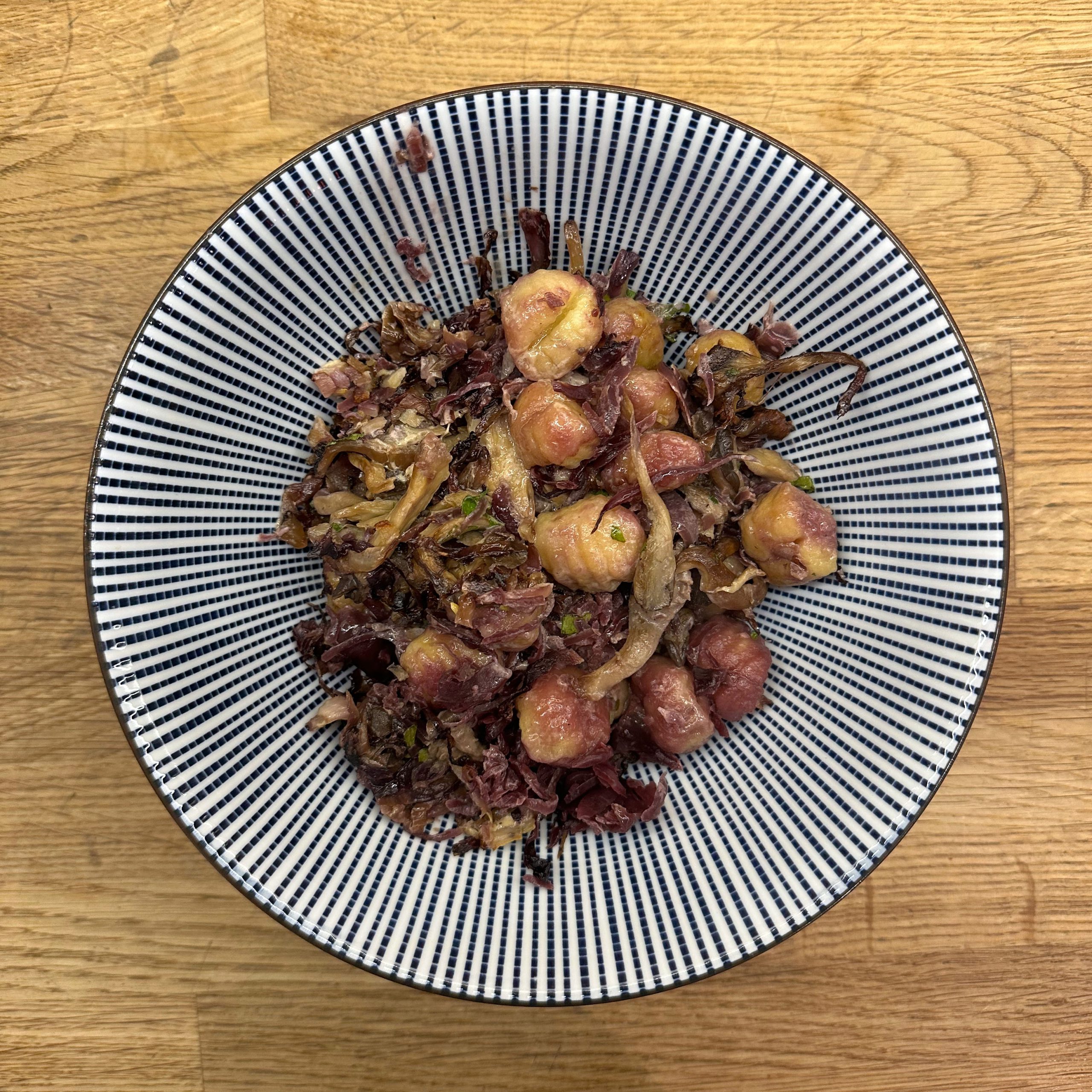 Überbackene Gnocchi mit Austernpilzen, Rotkohl und karamellisiertem Radicchio, serviert in einer schwarz-weiß gestreiften Schüssel auf einem Holztisch.