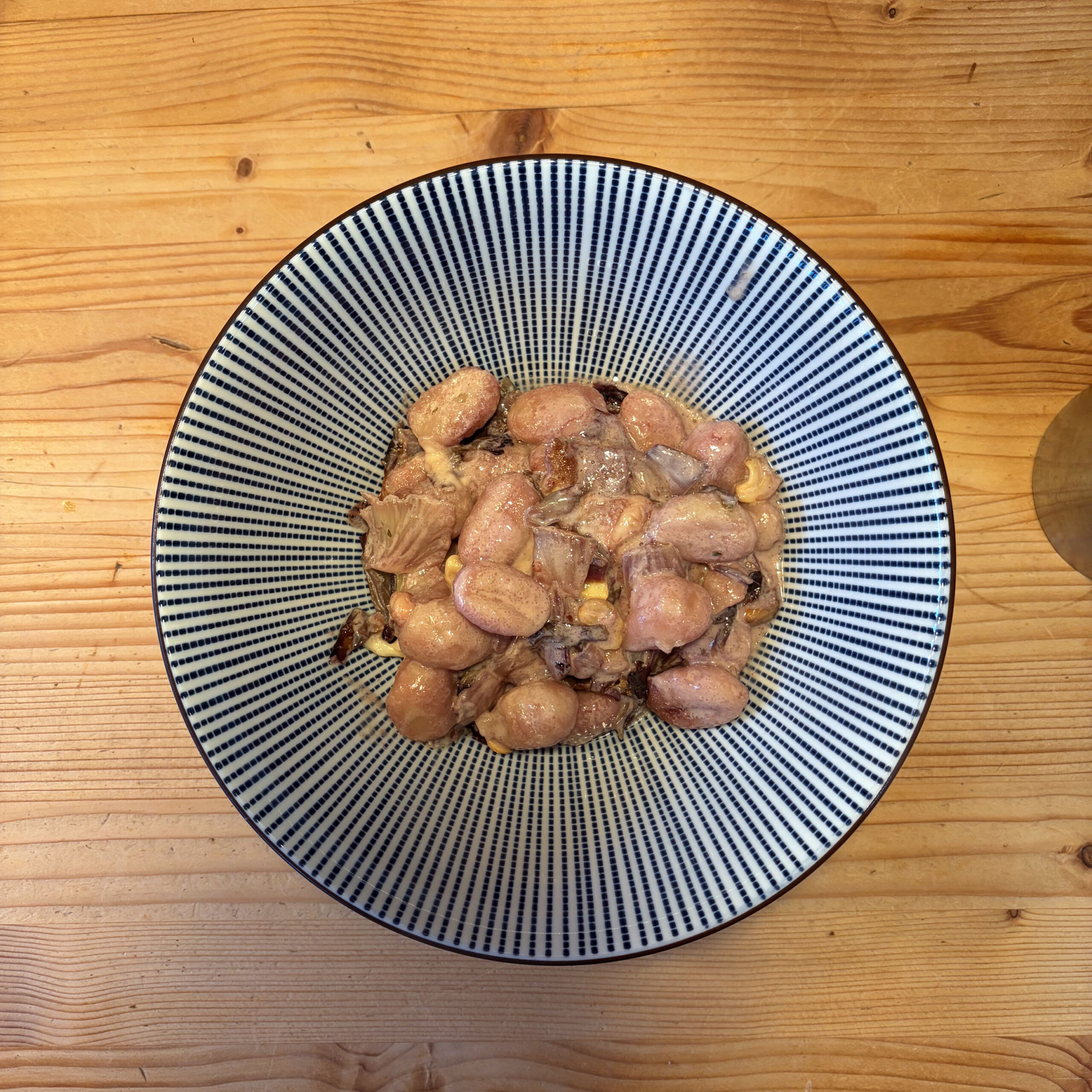 Gebackene Gnocchi mit angebratenem Radicchio und Mozzarella in einer blau-weiß gestreiften Schüssel auf einem Holztisch, von oben fotografiert.